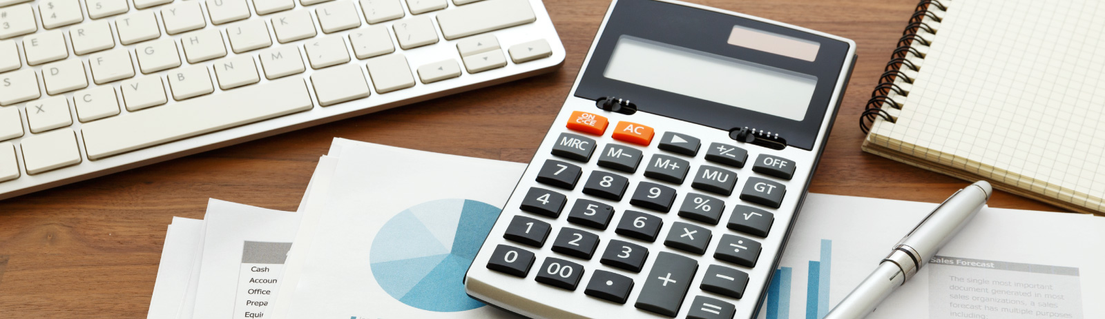 calculator next to a keyboard and notepad.