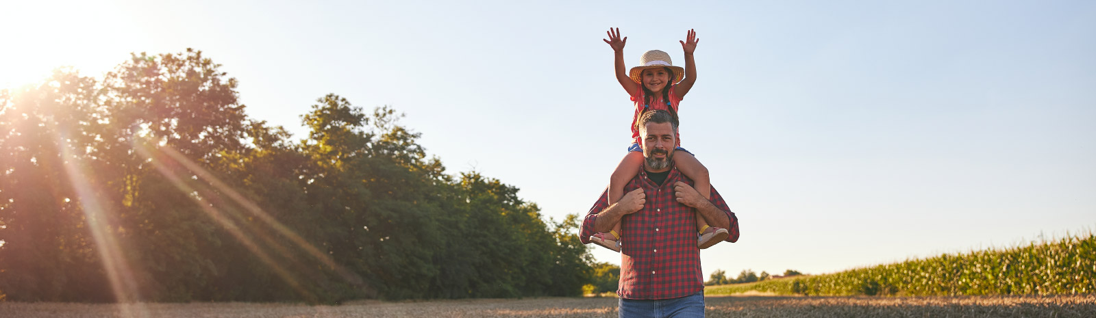 a little girl sitting on her father's shoulders with her hands in the air.